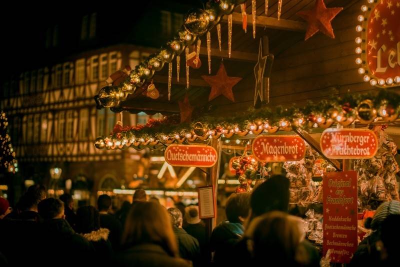 Cozy Christmas market stall adorned with festive lights and decorations, surrounded by a crowd enjoying the warm atmosphere.